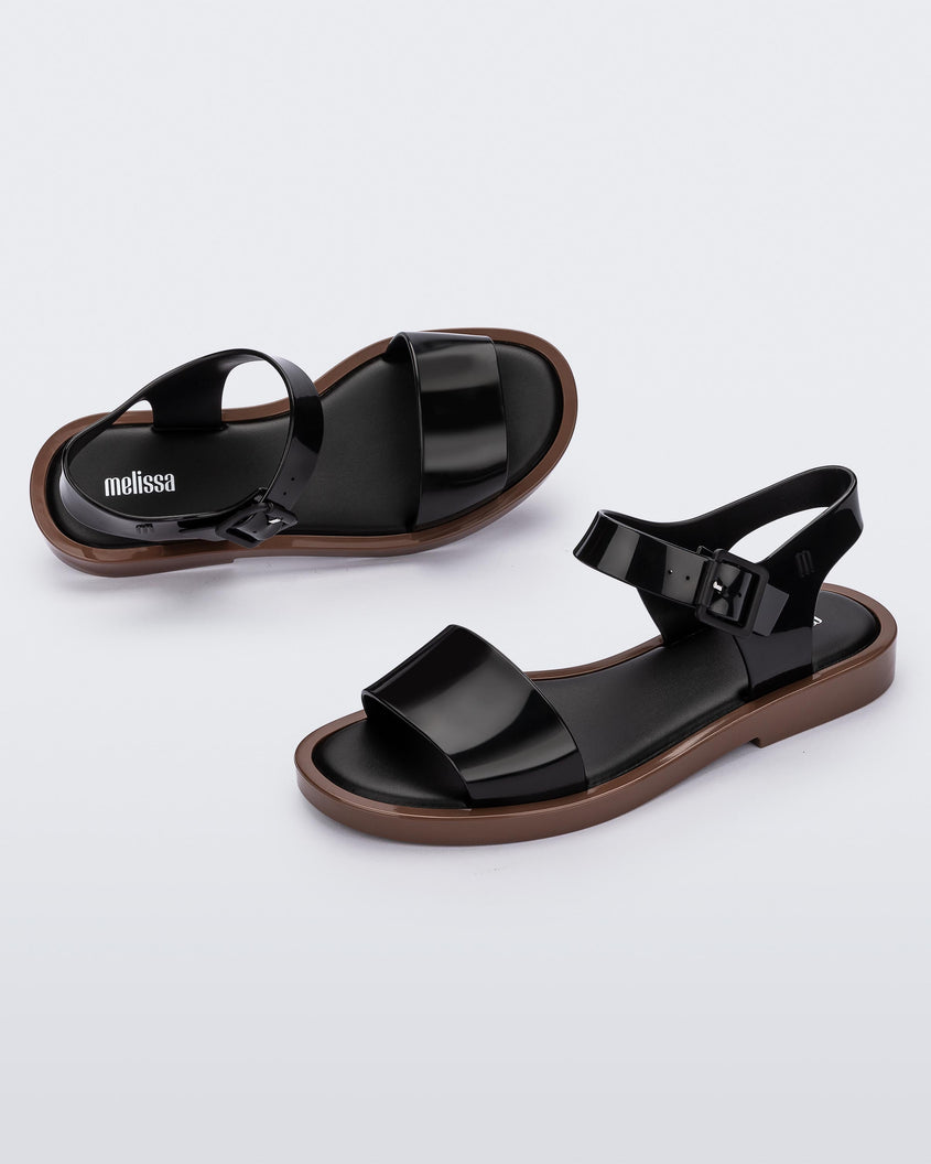 An angled front and side view of a pair of black/brown Melissa Mar sandals with two black straps and a brown sole.