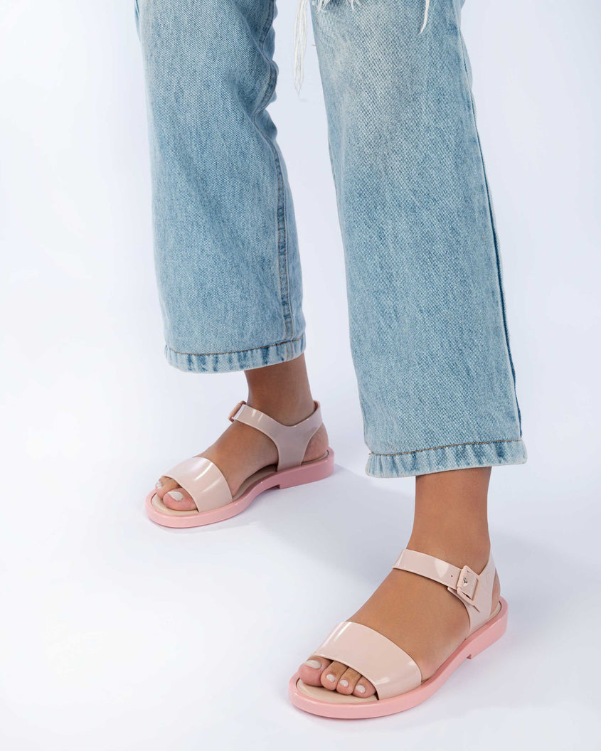 A model's legs wearing jeans and a pair of pink Melissa Mar Sandals with two straps.