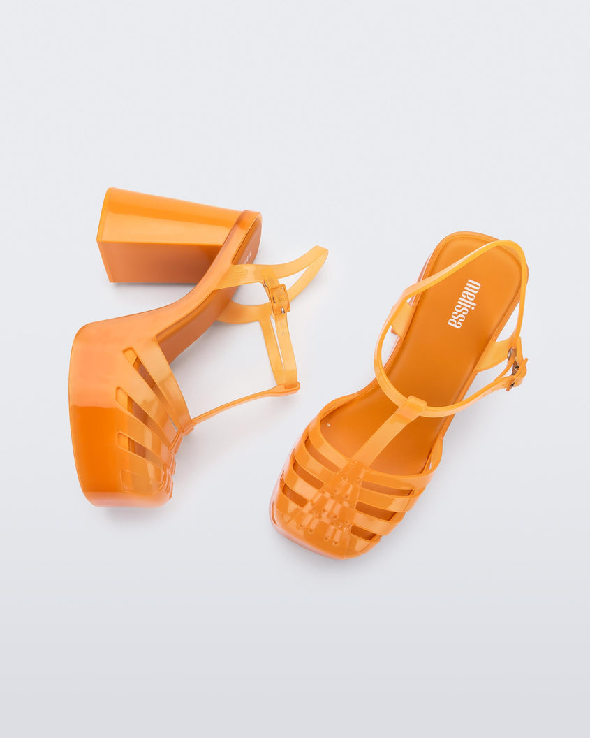 A top and side view of a pair of orange Melissa Party Heels with several straps and a closed toe front.