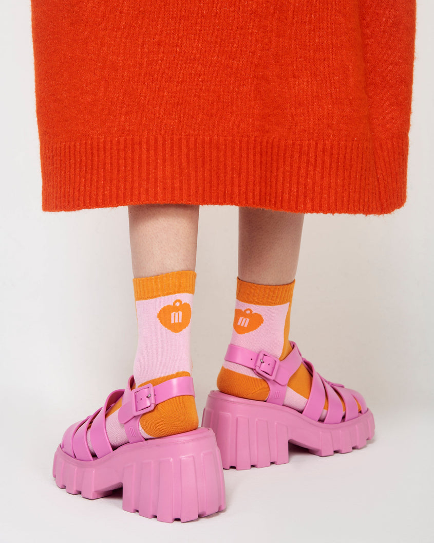 A model's legs wearing a pair of pink Melissa Megan platform heel sandals with socks.