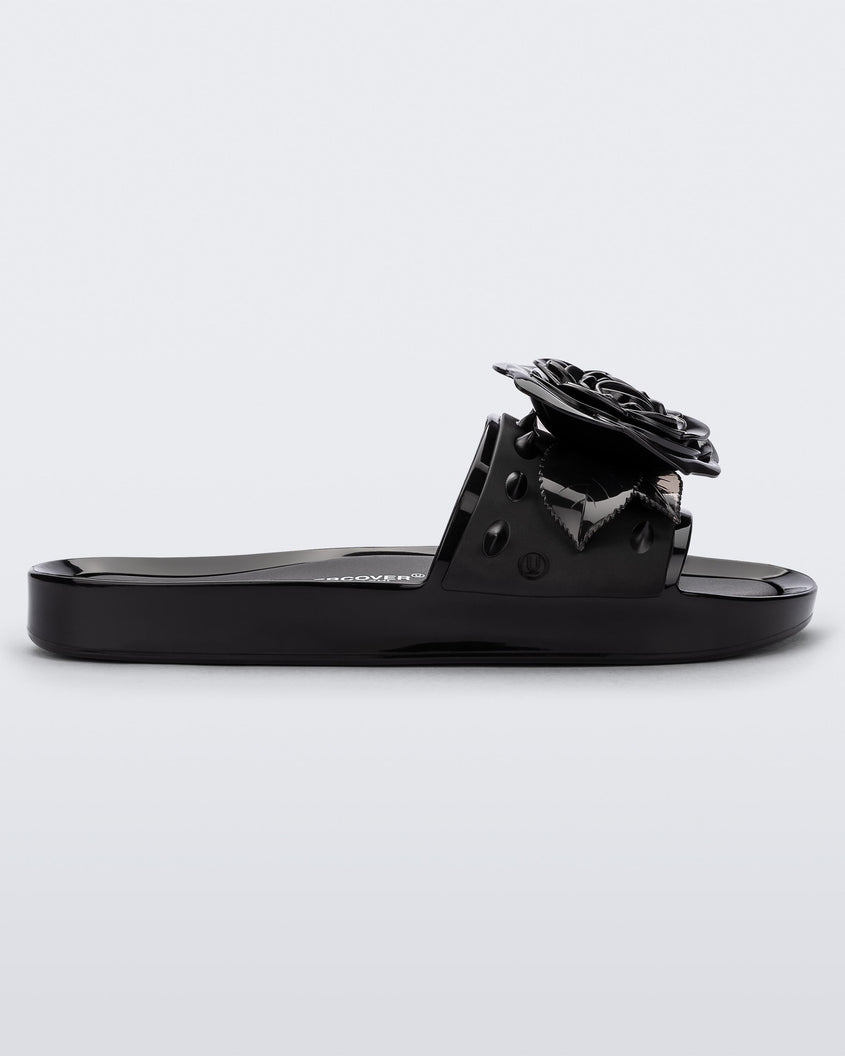 Side view of a black Melissa Spikes Beach slide with a flower detail and spikes on the front strap.