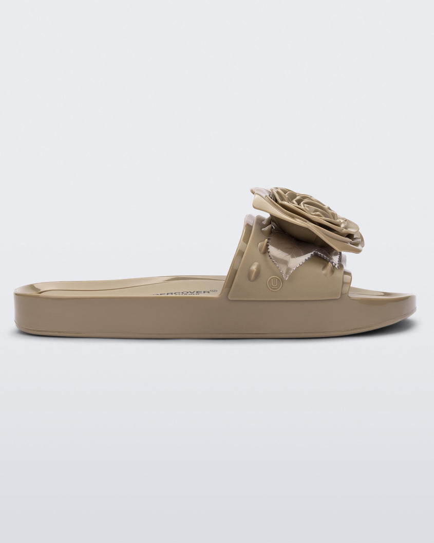Side view of a beige Melissa Spikes Beach slide with a flower detail and spikes on the front strap.