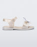 Side view of a metallic white Mini Melissa Mar Bugs sandal with a metallic white base, an ankle strap, front strap with a bug detail buckle on the front and a honey comb pattern sole.