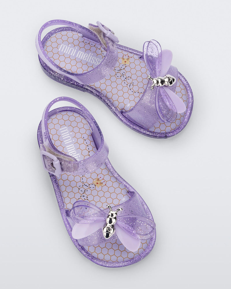Top view of a pair of lilac glitter Mini Melissa Mar Bugs sandals with a honeycomb pattern insole and a lilac bug detail with a silver buckle on the front.