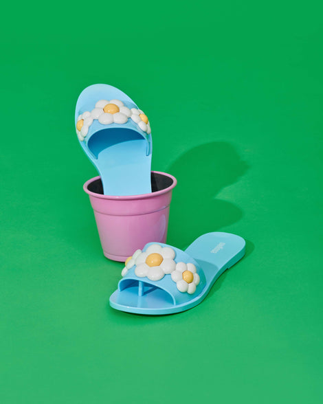 An angled shot of a pair of blue Melissa Babe Spring slides with white flowers.
