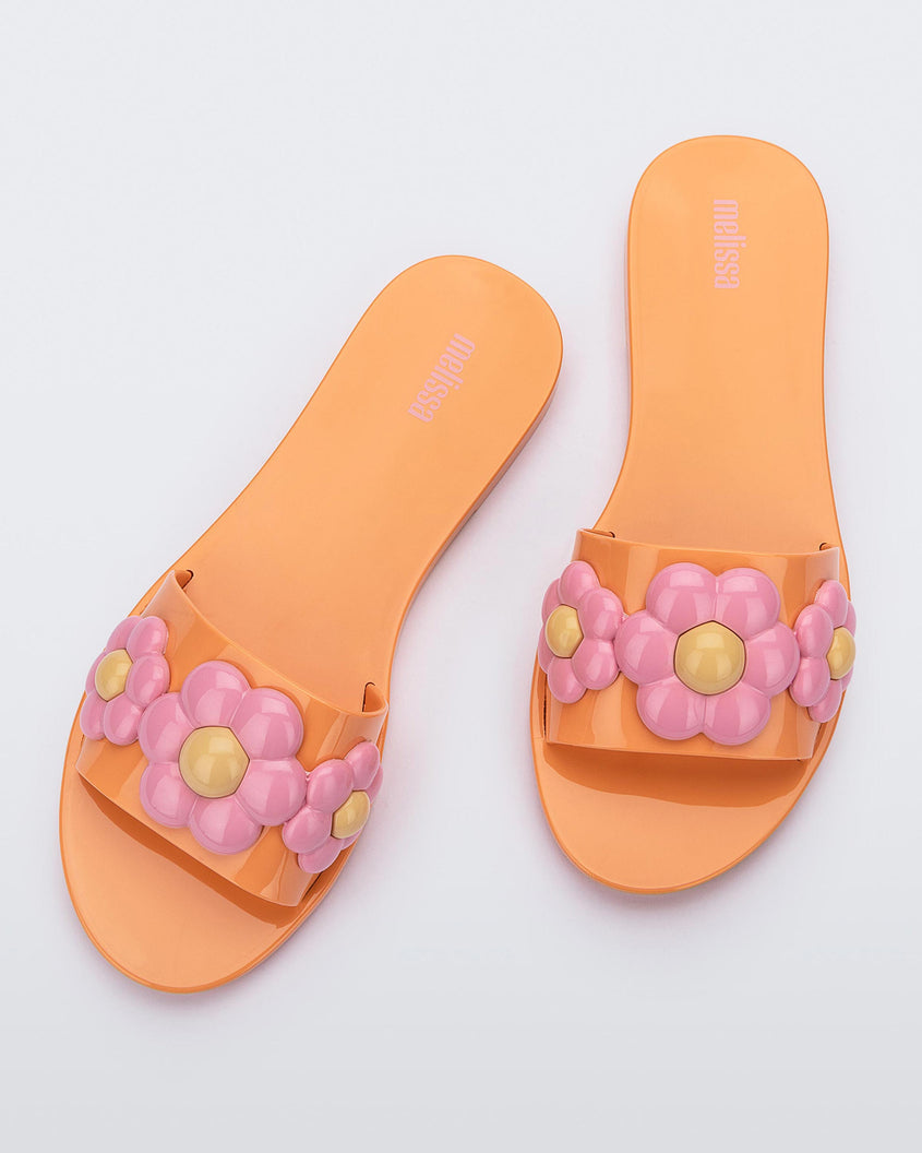 Top view of a pair of orange Melissa Babe Spring slide with pink flowers.