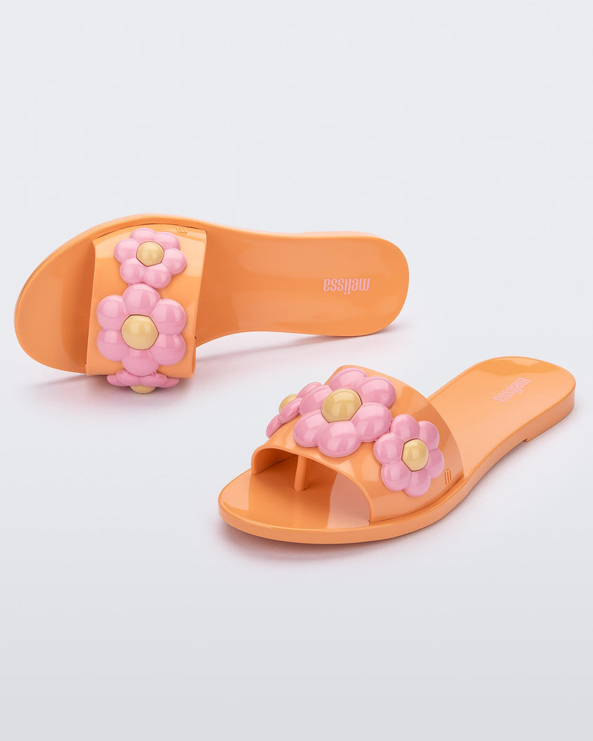 Top and angled view of a pair of orange Melissa Babe Spring slides with pink flowers.