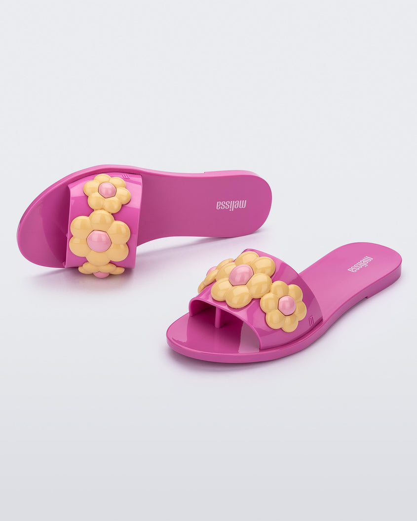 Top and angled view of a pair of purple Melissa Babe Spring slides with yellow flowers.