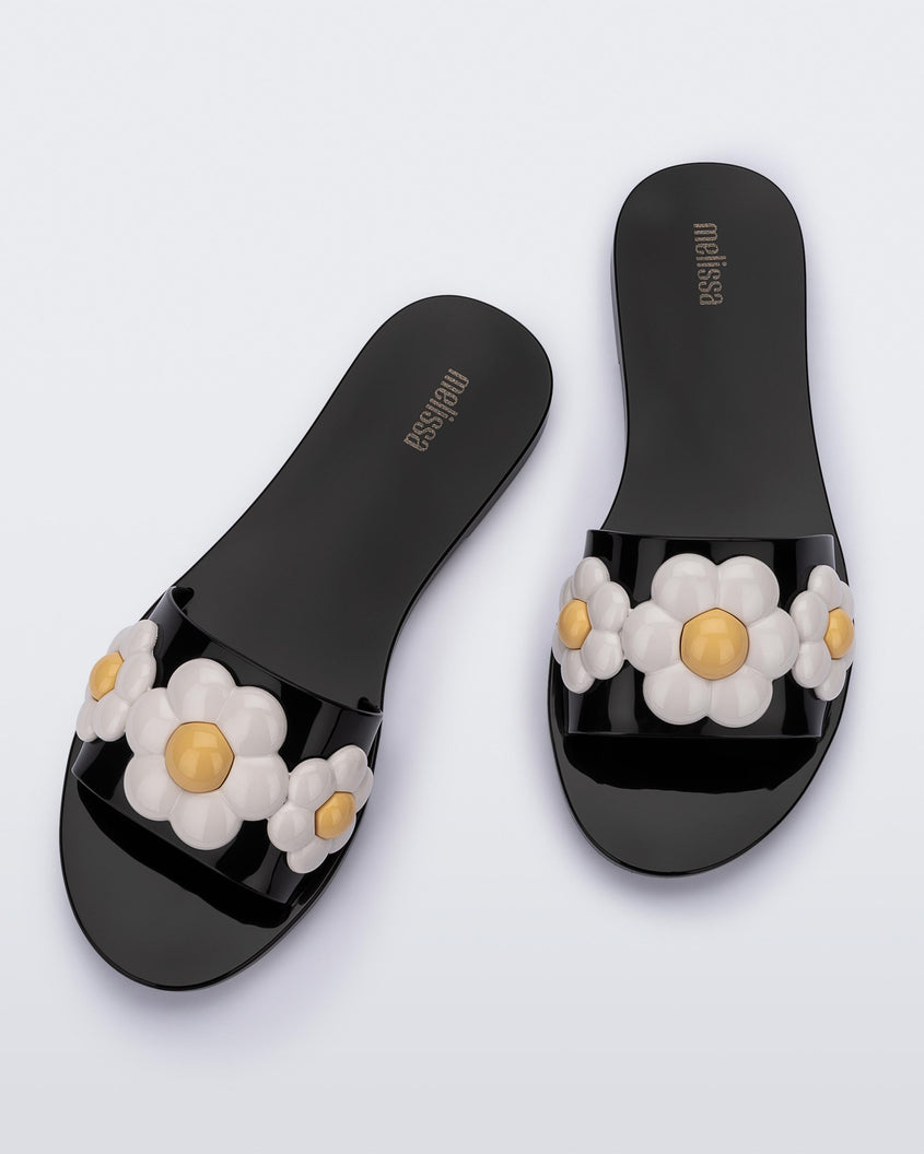 Top view of a pair of black Melissa Babe Spring slides with white flowers.