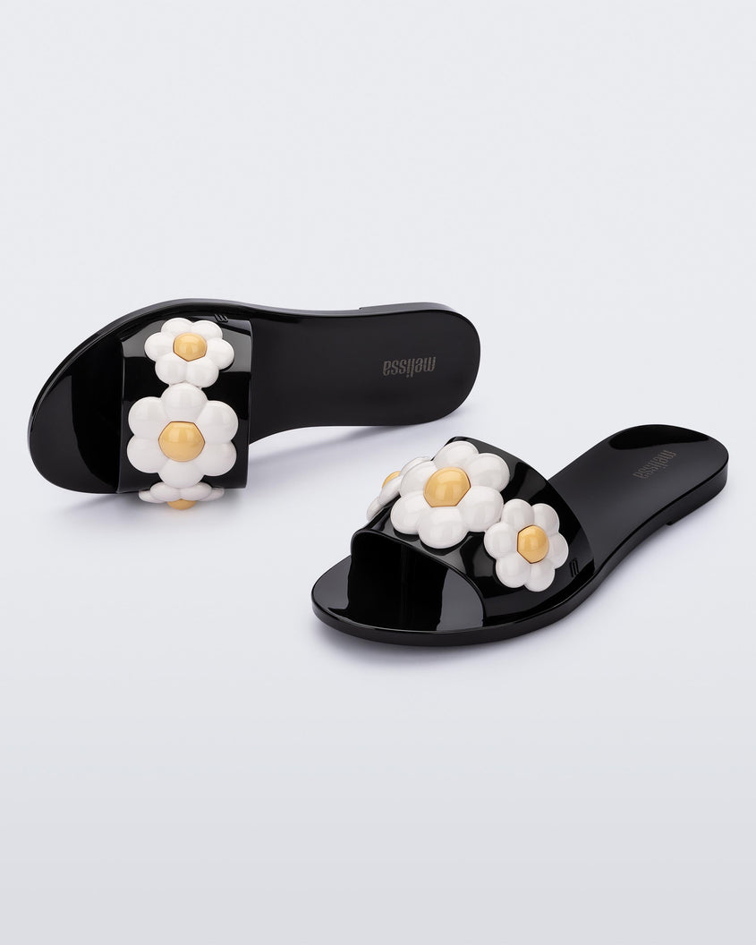 Top and angled view of a pair of black Melissa Babe Spring slides with white flowers.