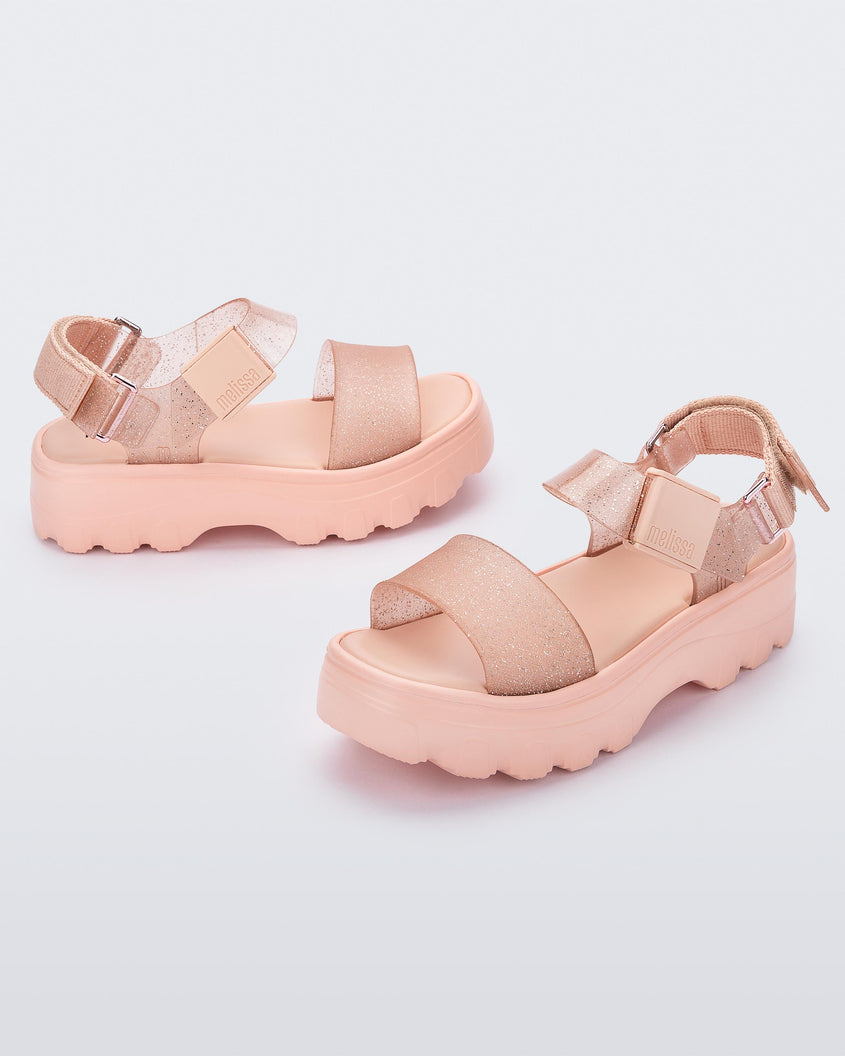 An angled top and side view of a pair of beige/glitter beige platform Melissa Kick Off Sandals with two straps.