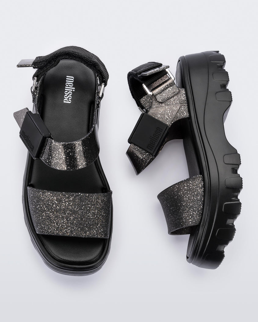 A top and side view of a pair of black/glitter black platform Melissa Kick Off Sandals with two glitter straps.