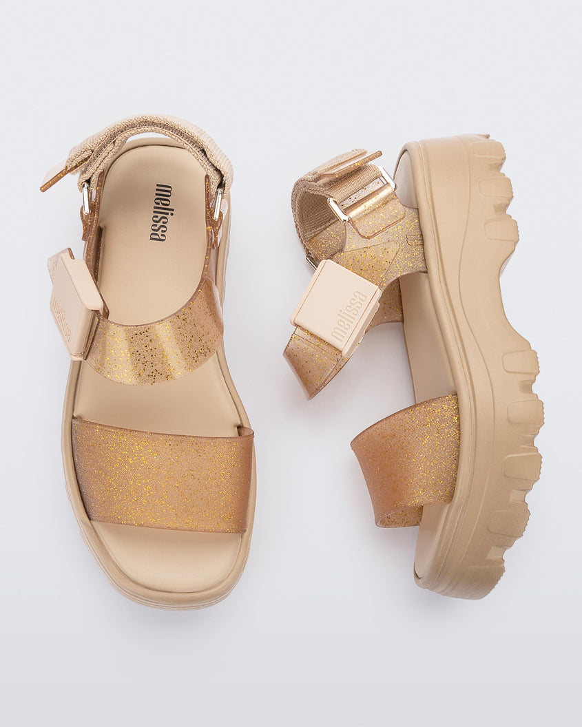 A top and side view of a pair of beige/gold platform Melissa Kick Off Sandals with two glitter straps.