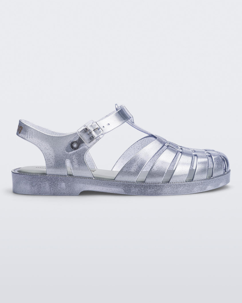 Side view of a silver Melissa Possession sandal with a closed toe front weft design connected to a top strap with a buckle.