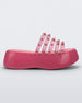 Side view of a Pink/Transparent Pink Melissa Punk Love Becky platform slide with a pink base and several top straps with spike stud details.