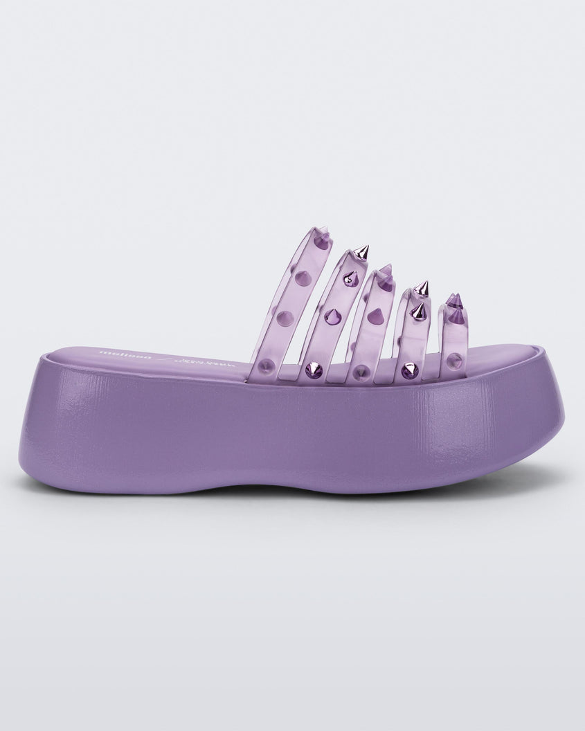 Side view of a violet / clear lilac Melissa Punk Love Becky platform slide with a lilac base and several top straps with spike stud details.