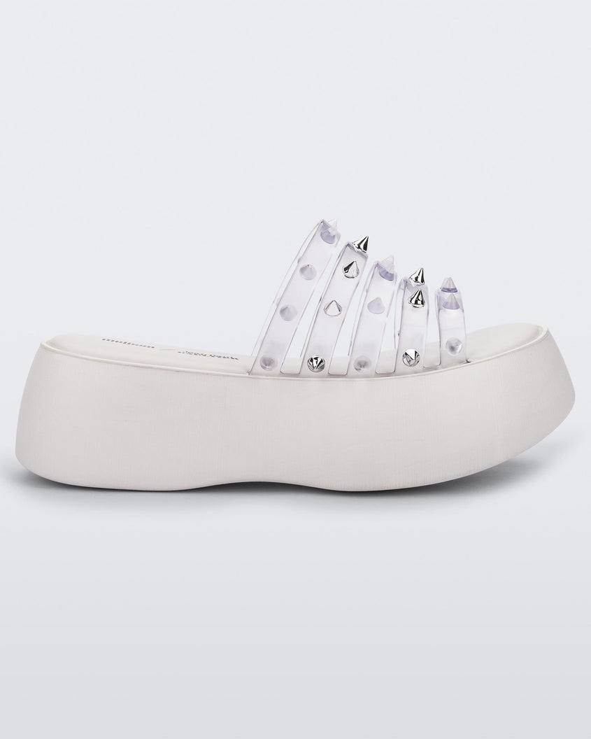 Side view of a White/Clear Melissa Punk Love Becky platform slide with a white base and several top straps with spike stud details.