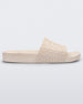 Side view of a beige Melissa Slide with the Marc Jacob's logo across the front strap.