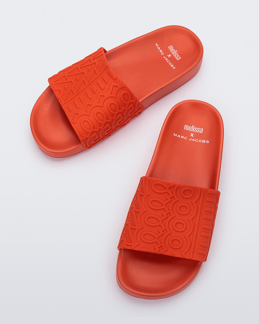 Top view of a red Melissa Slides with the Marc Jacobs logo across the front strap.