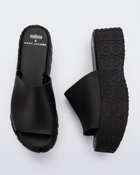 A top and side view of a pair of black Melissa Becky platform slides with the marc jacobs logo across the sole.