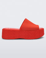 Side view of a red Melissa Becky platform slide with the marc jacobs logo across the sole.