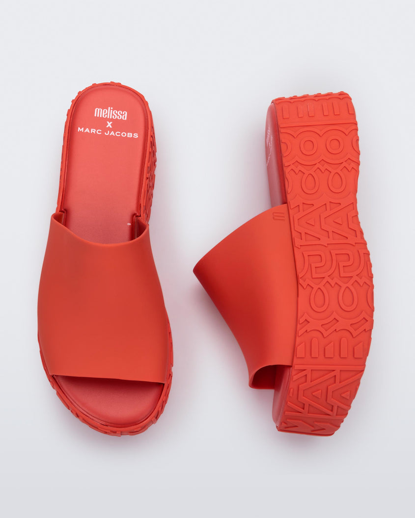 A top and side view of a pair of red Melissa Becky platform slides with the marc jacobs logo across the sole.