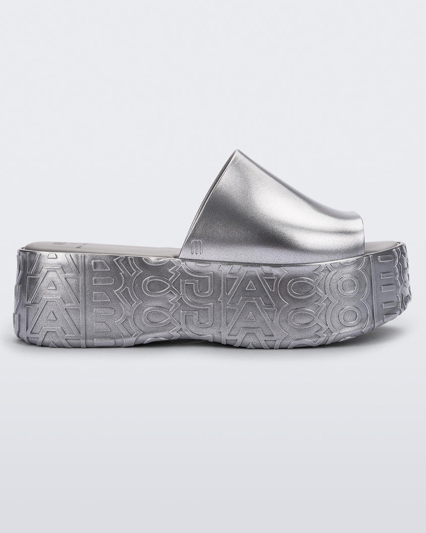 Side view of a silver Melissa Becky platform slide with the Marc Jacob's logo across the sole.