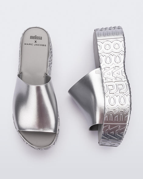 A top and side view of a silver Melissa Becky platform slides with the Marc Jacob's logo across the sole.