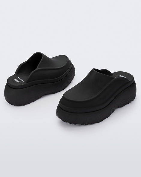 An angled front and back view of a pair of black Melissa Clogs with the Marc Jacob's logo across the sole.