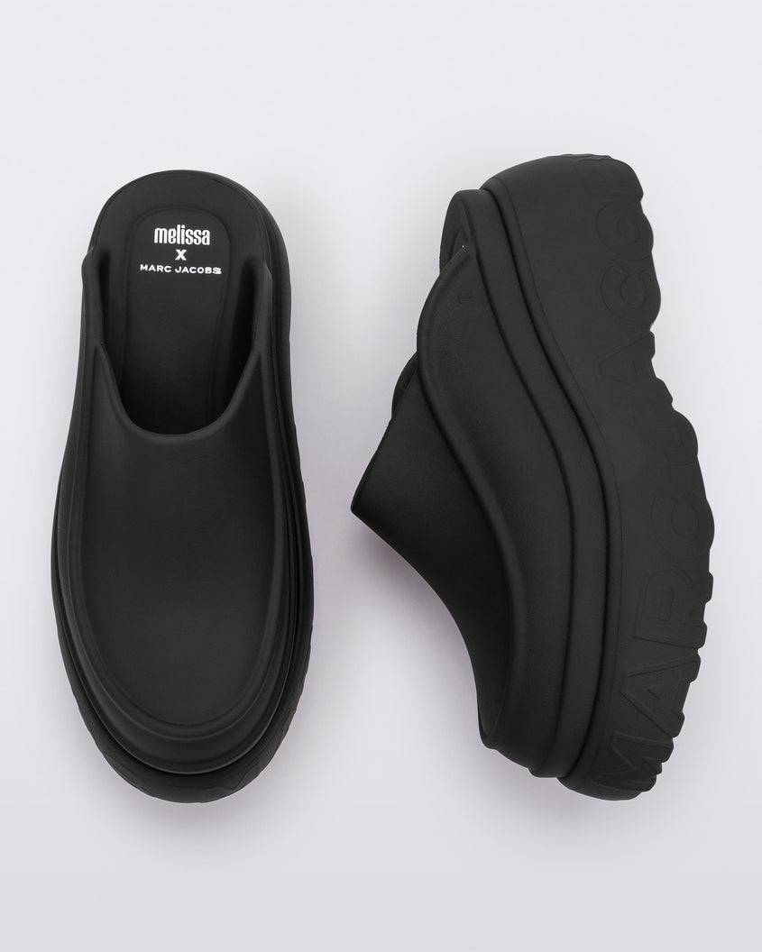 A top and side view of a pair of black Melissa Clogs with the Marc Jacob's logo across the sole.