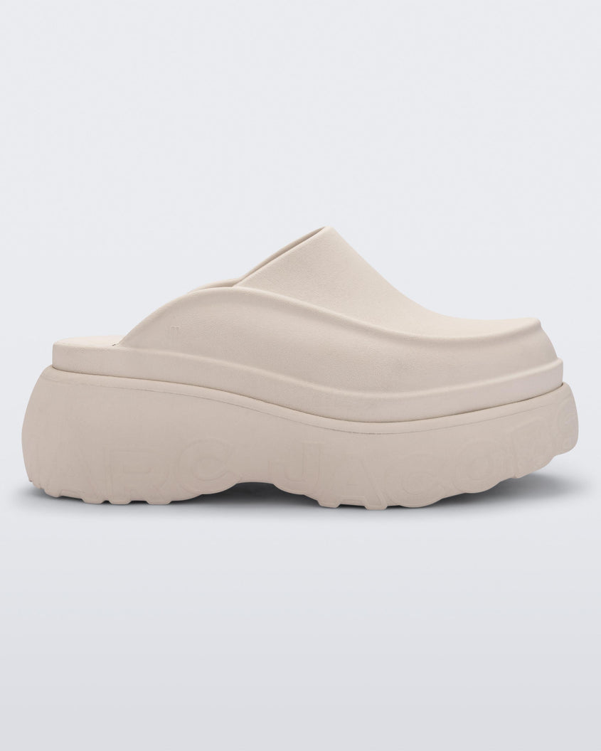 Side view of a beige Melissa Clog with the Marc Jacob's logo across the sole.
