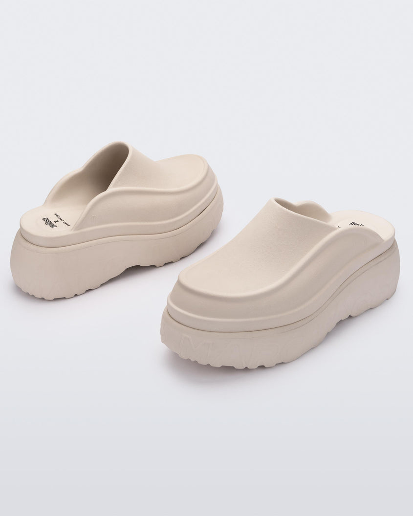 An angled front and back view of a pair of beige Melissa Clogs with the Marc Jacob's logo across the sole.
