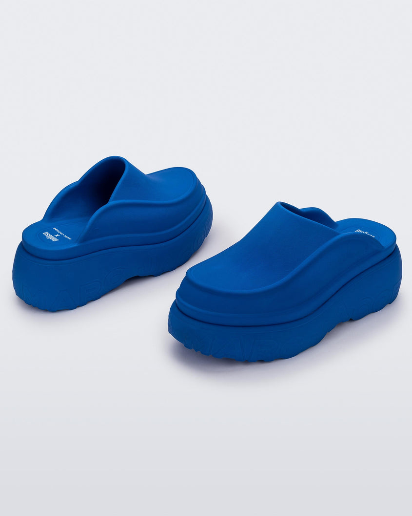 An angled front and back view of a pair of blue Melissa Clogs with the Marc Jacob's logo across the sole.