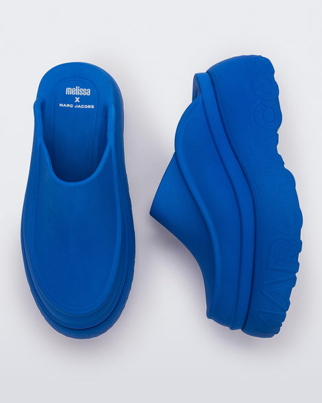 A top and side view of a pair of blue Melissa Clogs with the Marc Jacob's logo across the sole.