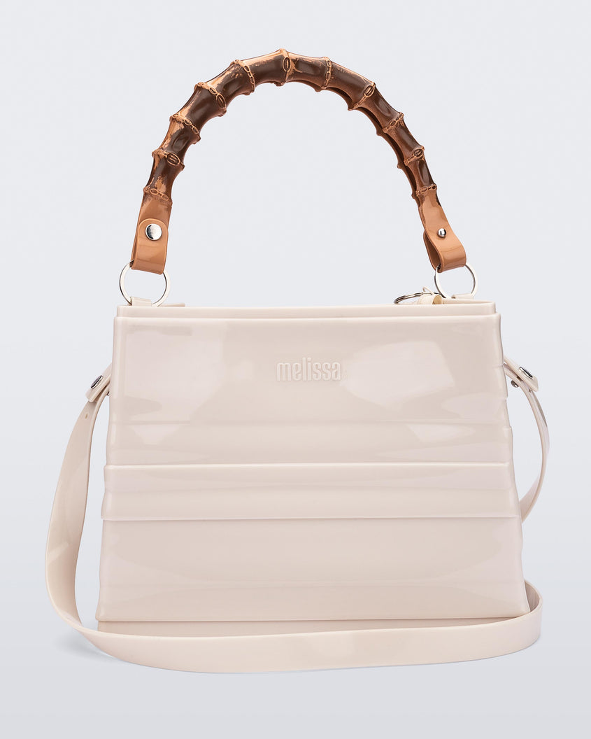 A back view of a beige Melissa Tie Bag with a bow detail on the front, two bamboo top straps and a beige shoulder strap.