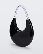 Angled view of the Melissa Moon Handbag. The body of the bag is crescent shaped and is black with a top zipper closer. There is a short shoulder handle that is clear / transparent material.