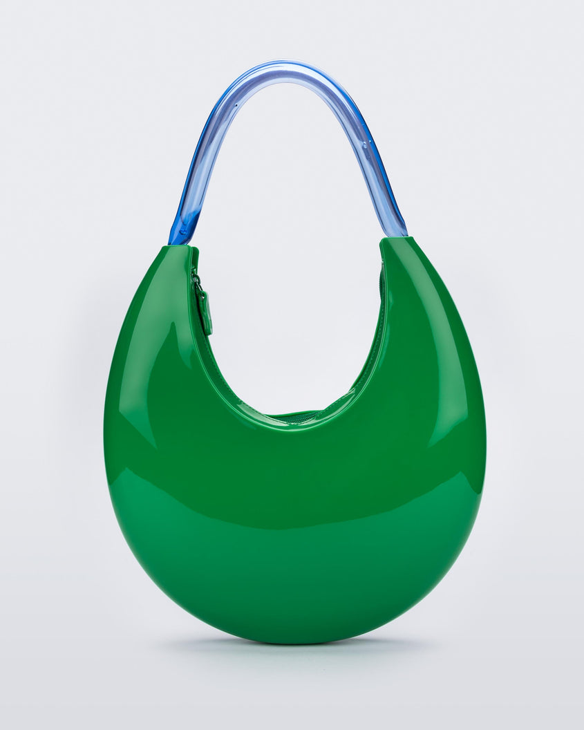 A zoomed in front view of a Green/Blue Melissa Moon Bag with a crescent shaped green bag base and a blue beige top strap.