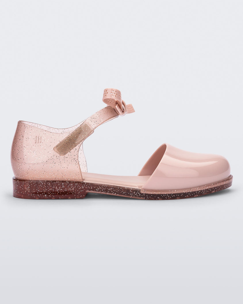 Side view of a pink Mini Melissa Amy sandal with a pink closed toe section and a back pink glitter strap with a lace like bow detail.