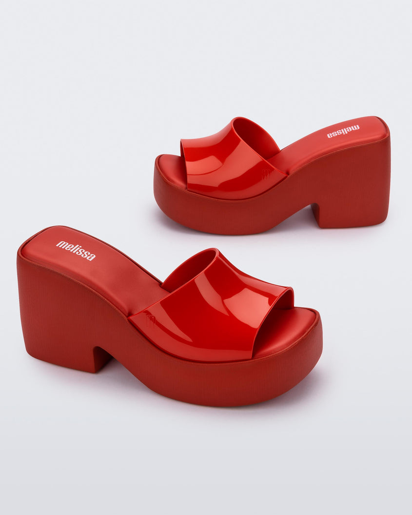 Angled view of a pair of Melissa Posh platform slides in Red