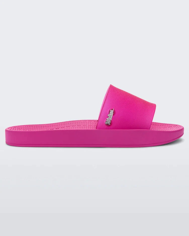 Side view of a pink/clear pink Melissa Sun Sunset slide with a melissa logo on the side.