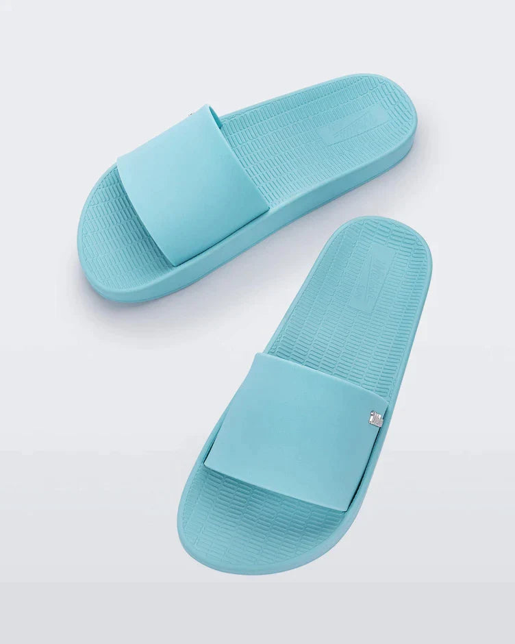 Top view of a pair of light blue Melissa Sun Sunset slides with a 