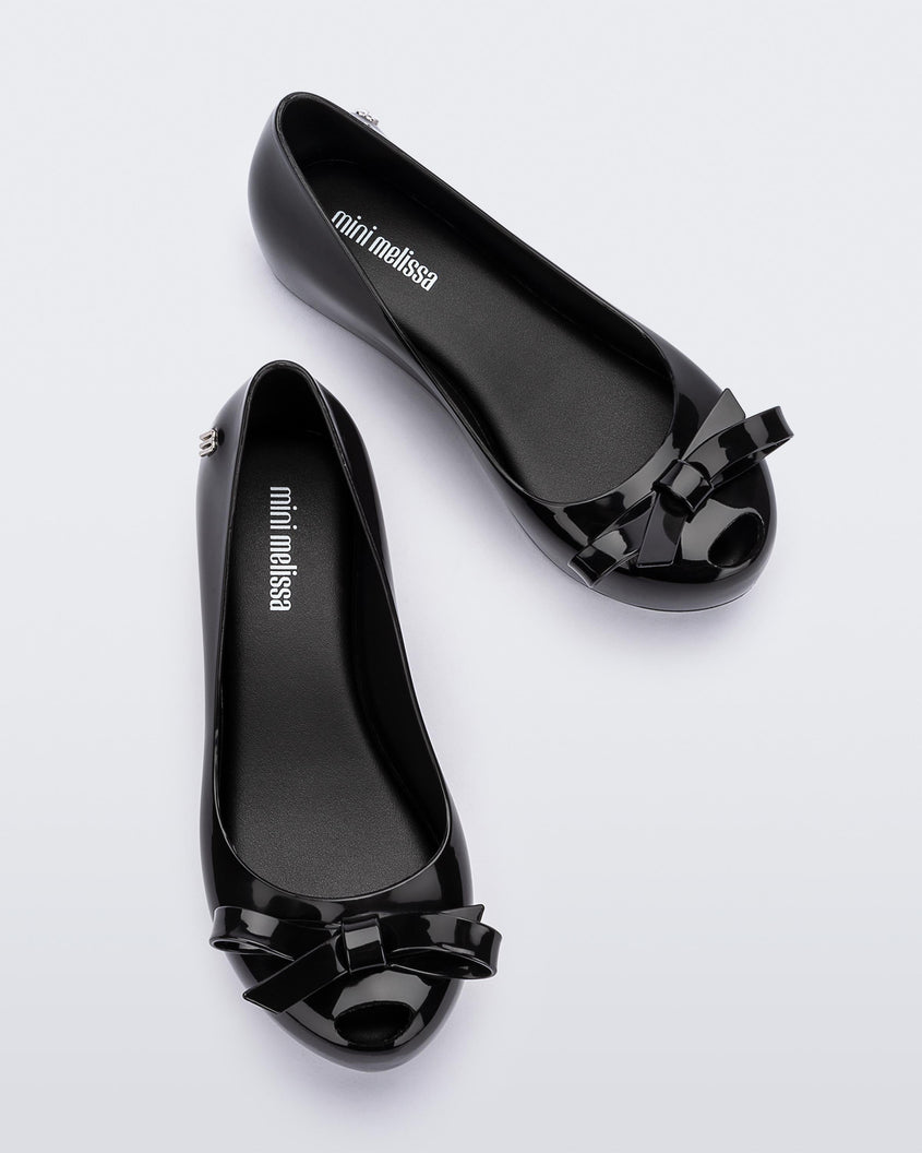 Top view of a Black Mini Melissa Ultragirl Bow flat with a black base and bow.