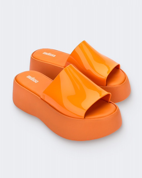 Angled view of a pair of orange Melissa Becky platform slides. 