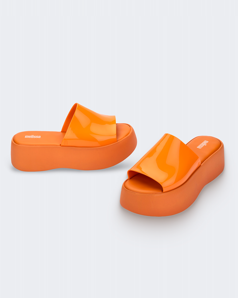 Angled view of a pair of orange Melissa Becky platform slides