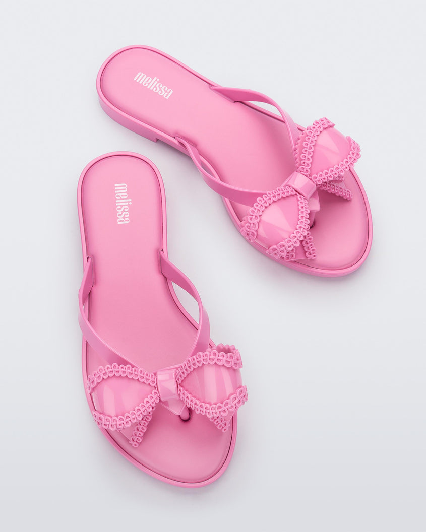Top view of a pair of Pink Melissa Slim flip flops with a bow detail on the front straps.