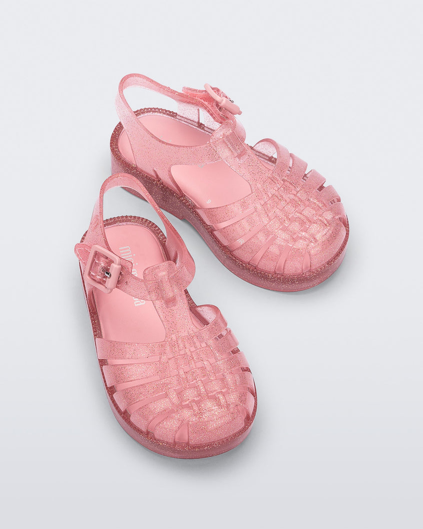 Top view of a pair of Glitter Pink Mini Melissa Possession sandals with several straps and a pink glitter base.