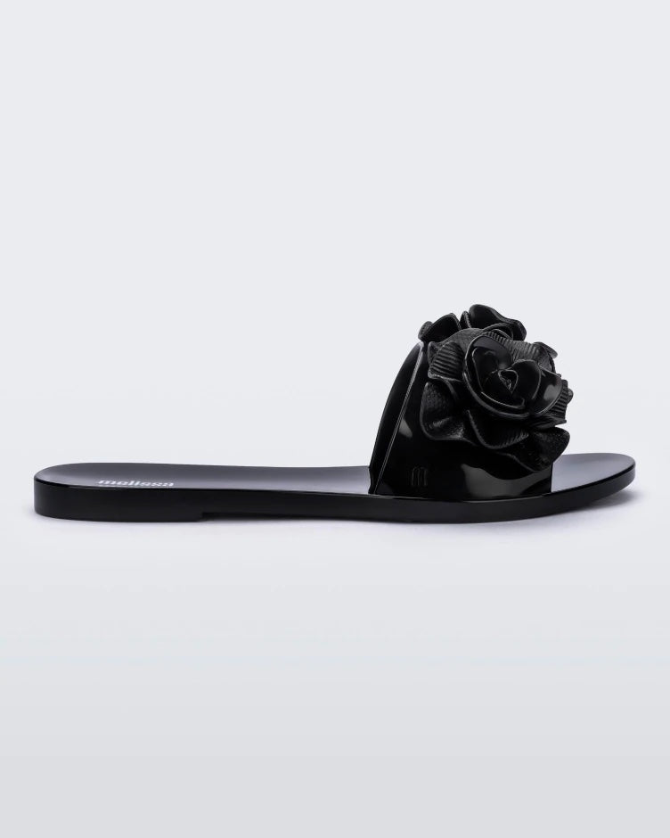 Side view of a black Melissa Babe Garden slide with two flowers on the front strap.