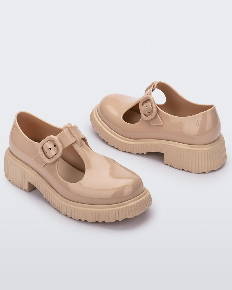 Angled side view of a pair of beige Mini Melissa Jackie loafers with two cut outs and a buckle detail strap.