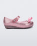 Side view of a Glitter Pink Mini Melissa Ultragirl Bow flat with a pink glitter base, top strap and pink bow on the toe.