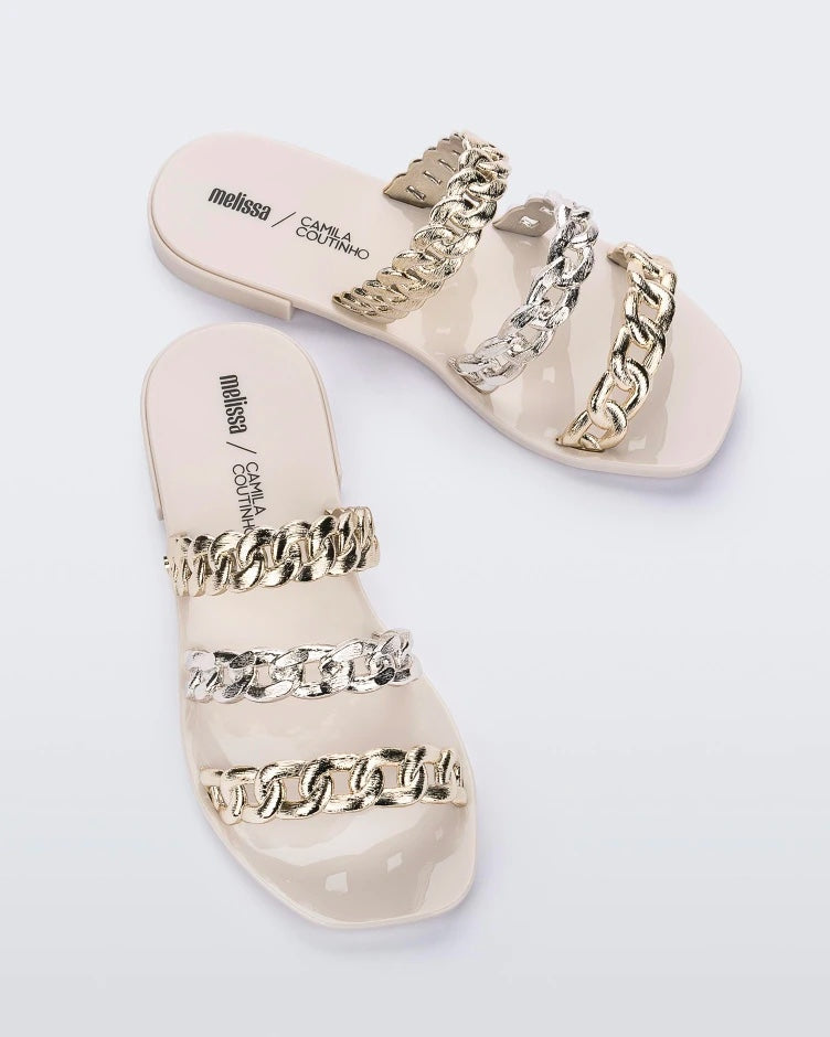 Top view of a pair of white Melissa Feel slides with three gold and silver chain detail straps.